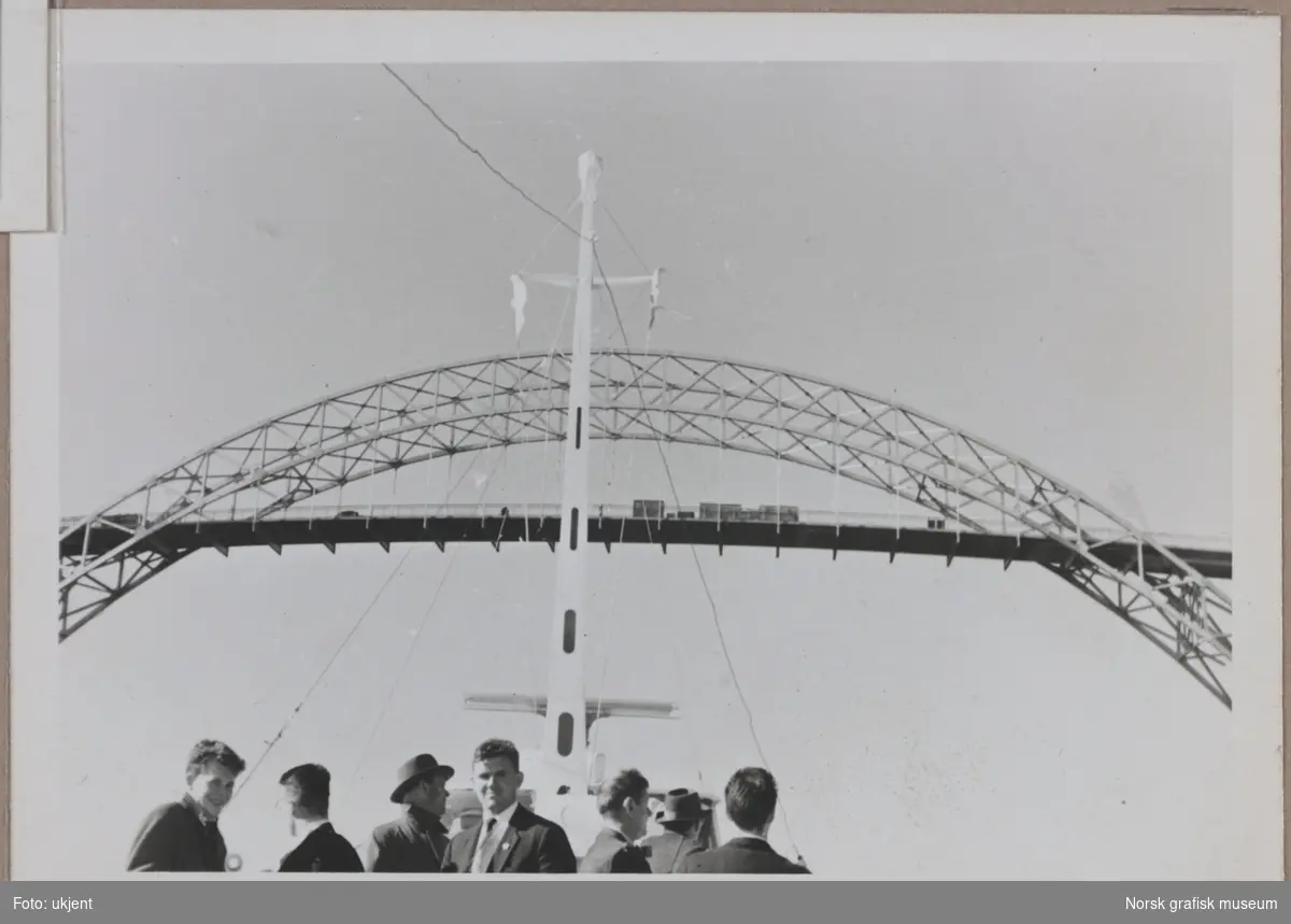 En gruppe menn titter opp på Karmsund bro fra et dekk, antageligvis på hurtigbåten mellom Haugesund og Stavanger. Det ser ut til at å være byggearbeider på broa.