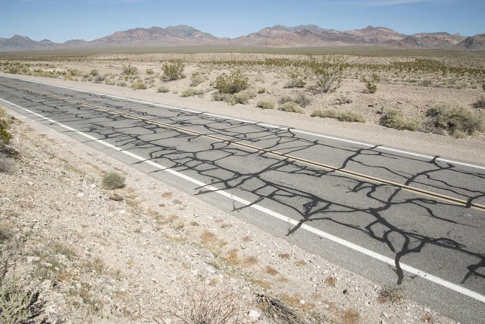 A paved road slopes through a desert landscape.