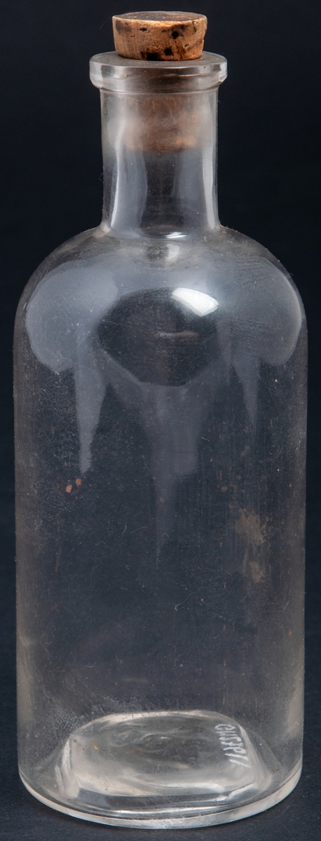 Flaska av ofärgat glas med kork. Åttakantig försänkning i botten märkt "200". Medicinflaska (?)