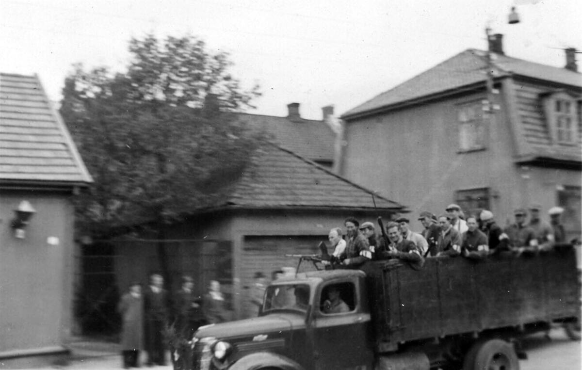 Fra frigjøringsdagene etter 2. verdenskrig. Lastebil med menn på lasteplanet kjører i gaten.