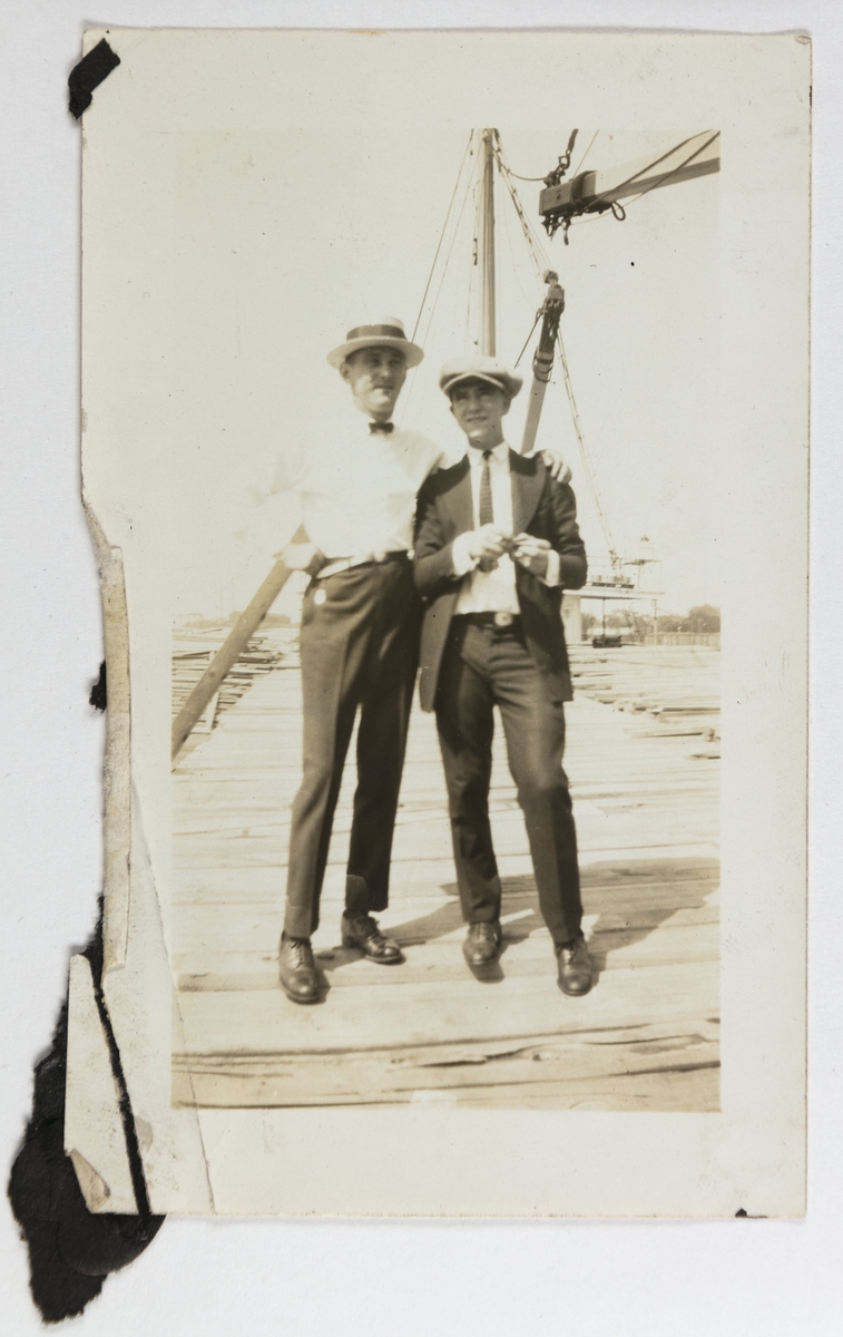 To unge menn står på en trelast med et skip i bakgrunnen, antageligvis ved Chicago River.