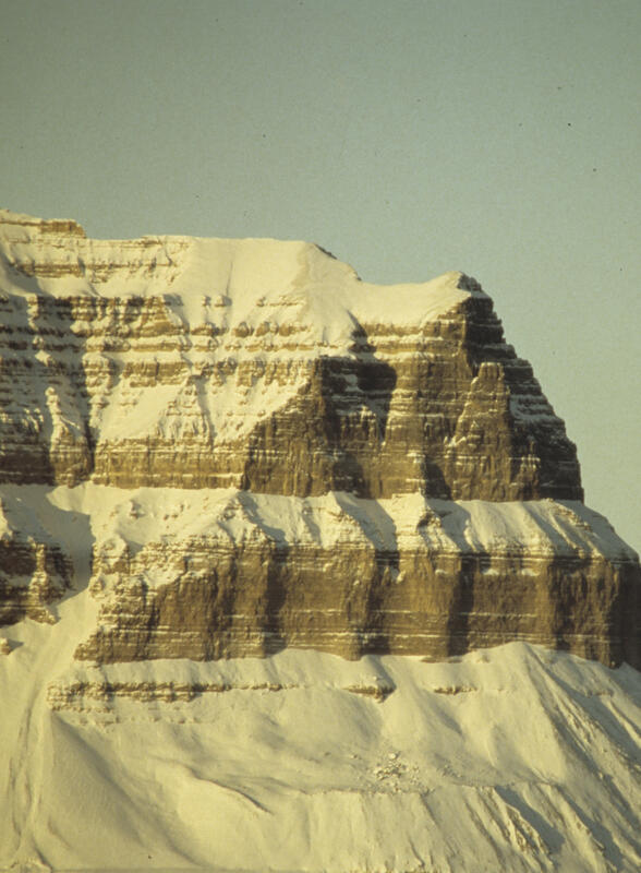 Bildet viser en snødekt klippe, der de ulike lagene i fjellet vises tydelig.