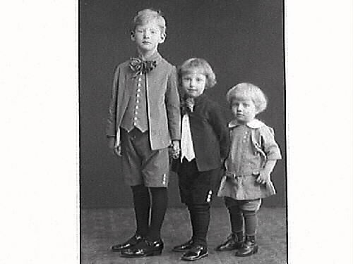 Komminister Aronius fru och tre söner. Barnen bär kortbyxor, strumpor och skor. Den minste är klädd i kolt med de två äldre har korta rockar, västliknande skjortor och stora halsrosetter.