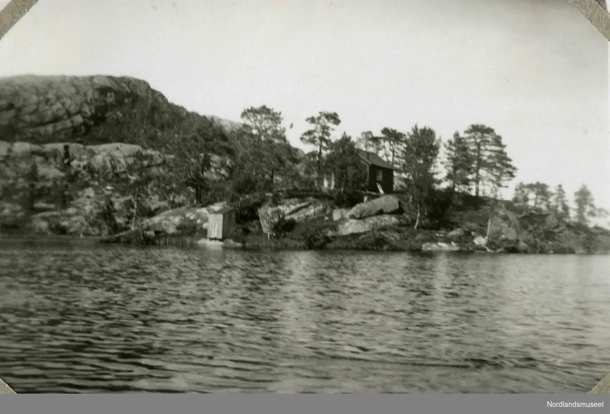 Liten hytte og utedo fotografert fra båt. Tekst i album: Ved Bordstolvatnet 1936. Slottet på øen.