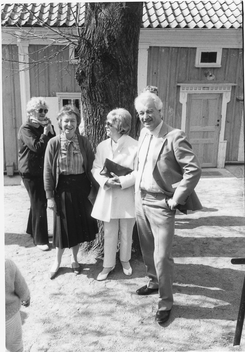 Tre kvinnor och en man står vid linden på Grenna Museums gård.