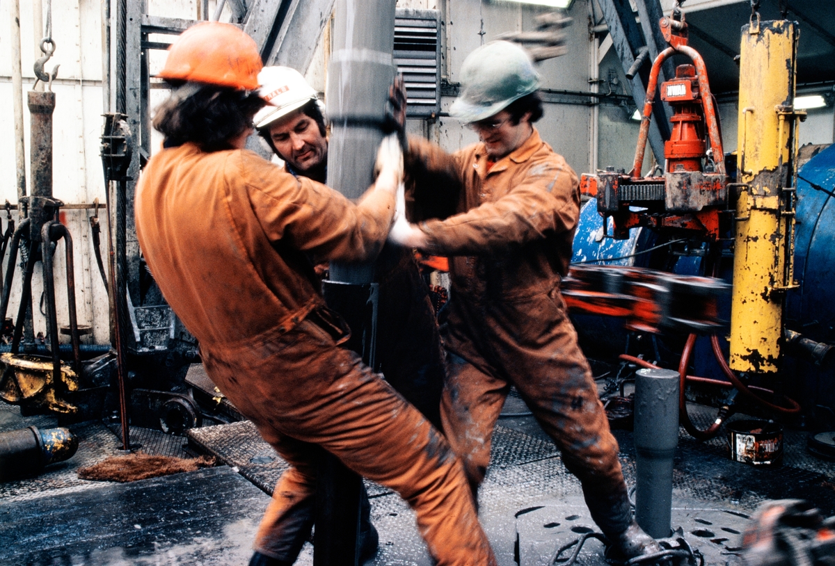 Oljearbeidere håndterer et borerør.