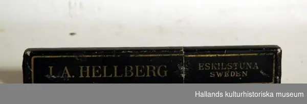 a) Rakkniv av stål, krämfärgat skaft av bakelit. Längd 15 cm. b) Svart fodral av papp, märkt: "JA Hellberg, Eskilstuna, Sweden".