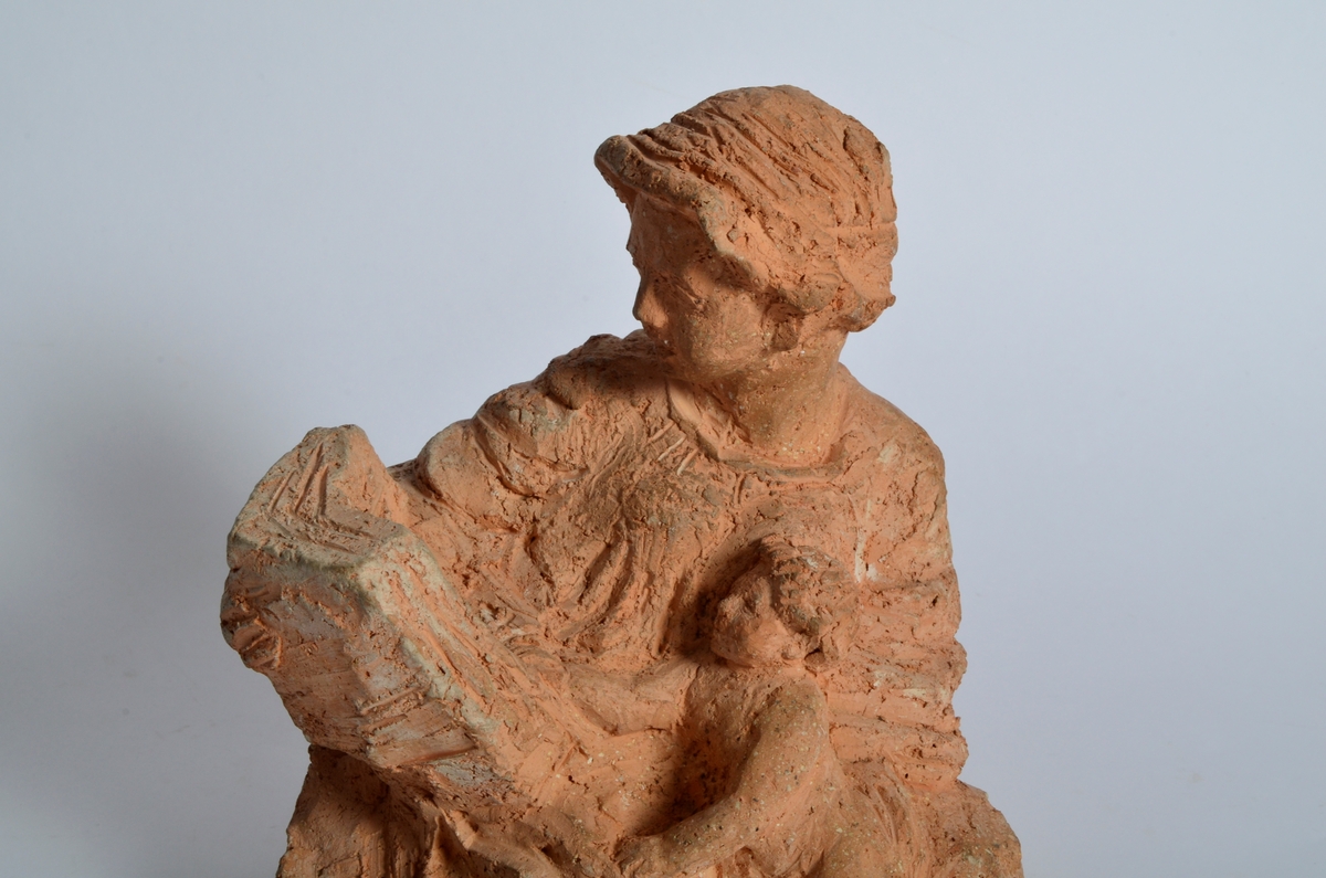 Terrakottafigur som visar ei stjande kvinne som les for eit born. Motiv frå teikning Michelangelo eller Rafael.