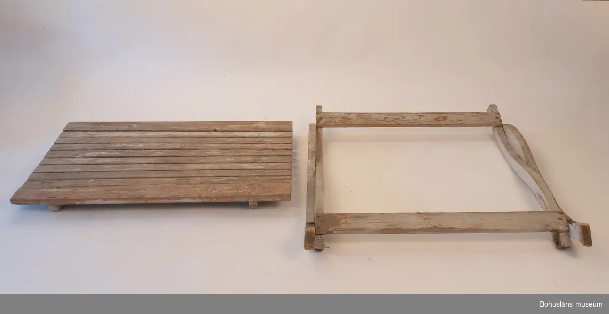 Vitmålat träbord, hopfällbart. Rektangulär bordsskiva av platta spjälor. Dekorativt utformade benavslut.
Delvis trasigt.
Samhör med UM032293 Stol.