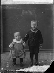 To barn fotografert i studio. Barnet til venstre er kledd i 
