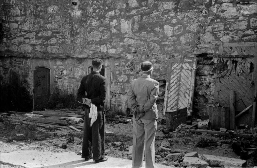 To mannlige figuranter står på stedet ved festningsmuren, der motstandsfolk ble henrettet under 2. verdenskrig.