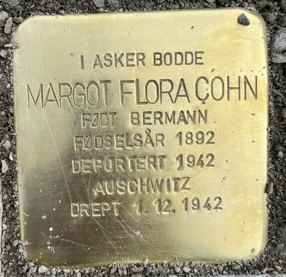 Bronse plate med inskripsjon: I Asker bodde Margot Flora Cohn født Bergmann. Fødselsår 1892. Deportert 1942. Auschwitz. Drept 1.12.1942