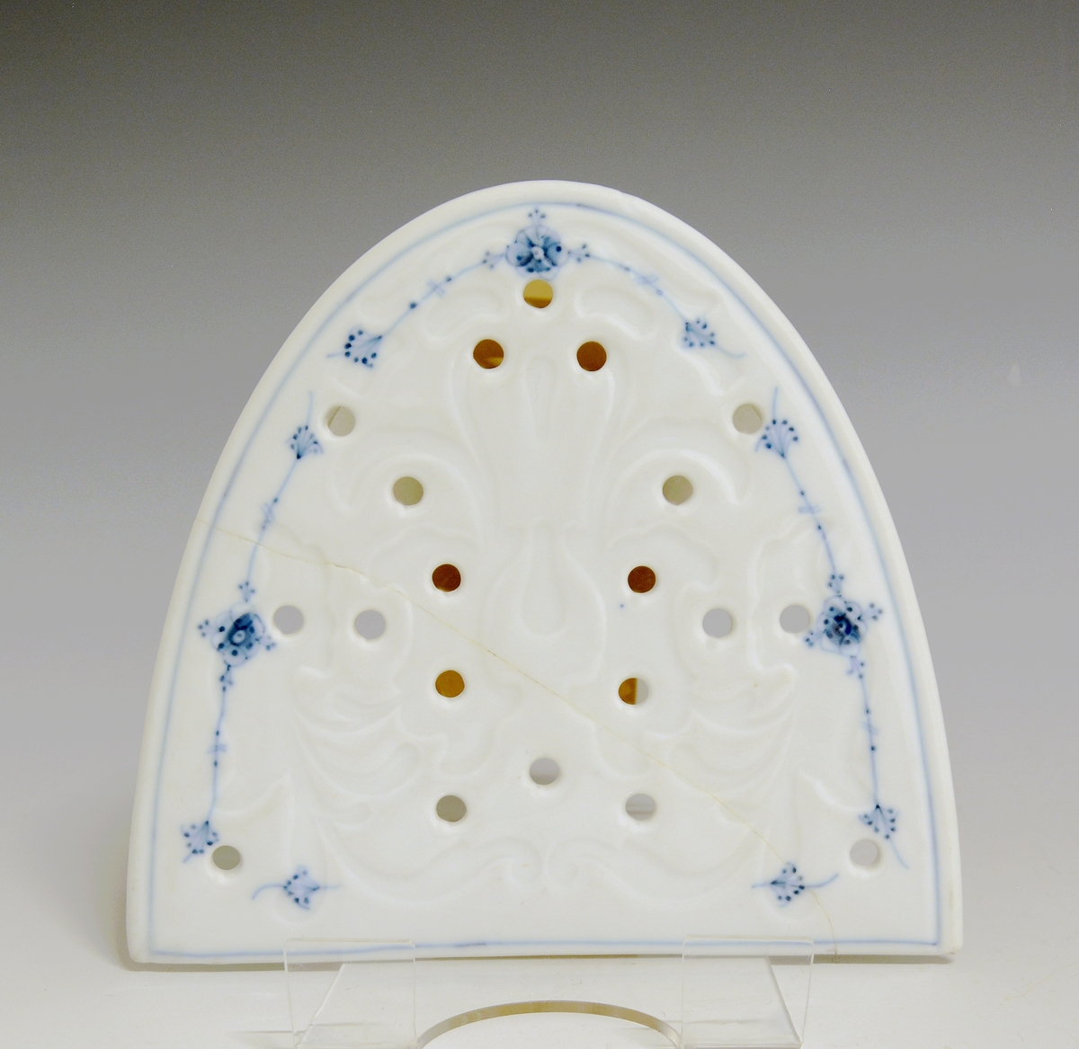 Fiskerist av porselen. Rett avskåret oval plate, med et større og flere små hull i godset. Hvit glasur, dekorert med stråmønster i blått.

Modell: 1123