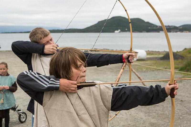 To barn i vikingklær skyter med pil og bue