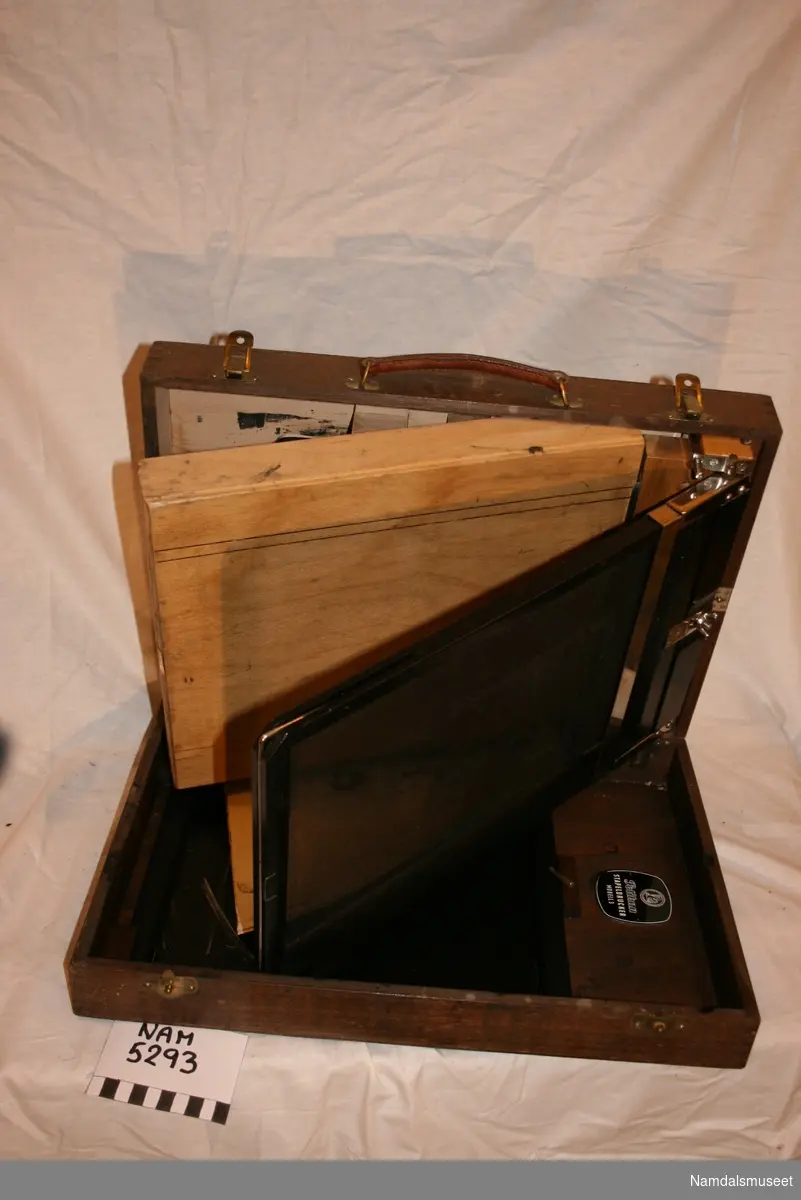 Kopimaskinen er montert i en rektangulær boks med lokk.