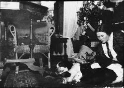 Kvinne  på gulvet i en stue, sammen med hund og katter. Jule