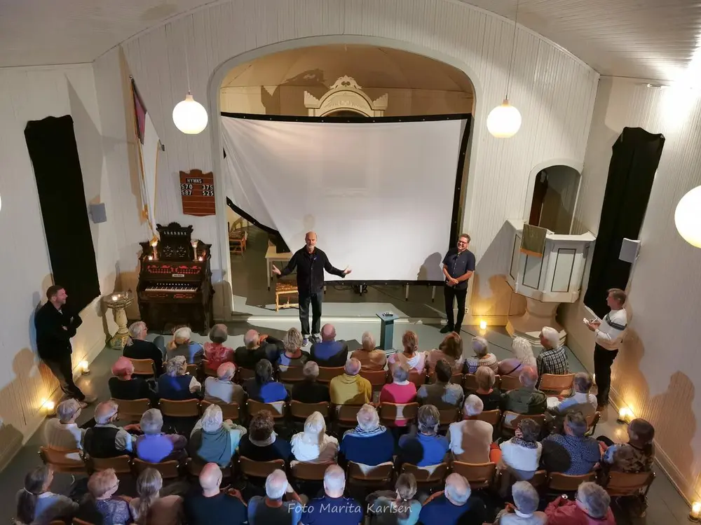 Erik Poppe står foran publikum og snakker.