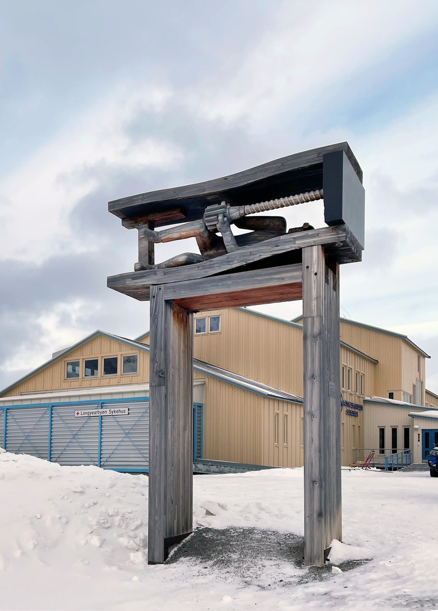 På plassen foran hovedinngangen står "Gruvearbeideren" av Kristian Kvakland. Skulpturen viser en gruvearbeider i liggende borestilling i en lav strosse. Kvakland var opptatt av at verket skulle formidle et mest mulig korrekt bilde av gruvearbeidet, og han besøkte blant annet Gruve 7 i Longyearbyen og Svalbardmuseet, hvor en tidligere gruvearbeider demonstrerte ulike borestillinger.

"Gruvearbeideren" er laget i utskåret furu og Iddefjordsgranitt, og står på en to meter høy sokkel i laminert furu. Materialenes røffe uttrykk speiler omgivelsene og bærer sterkt preg av stedets lokale historie.