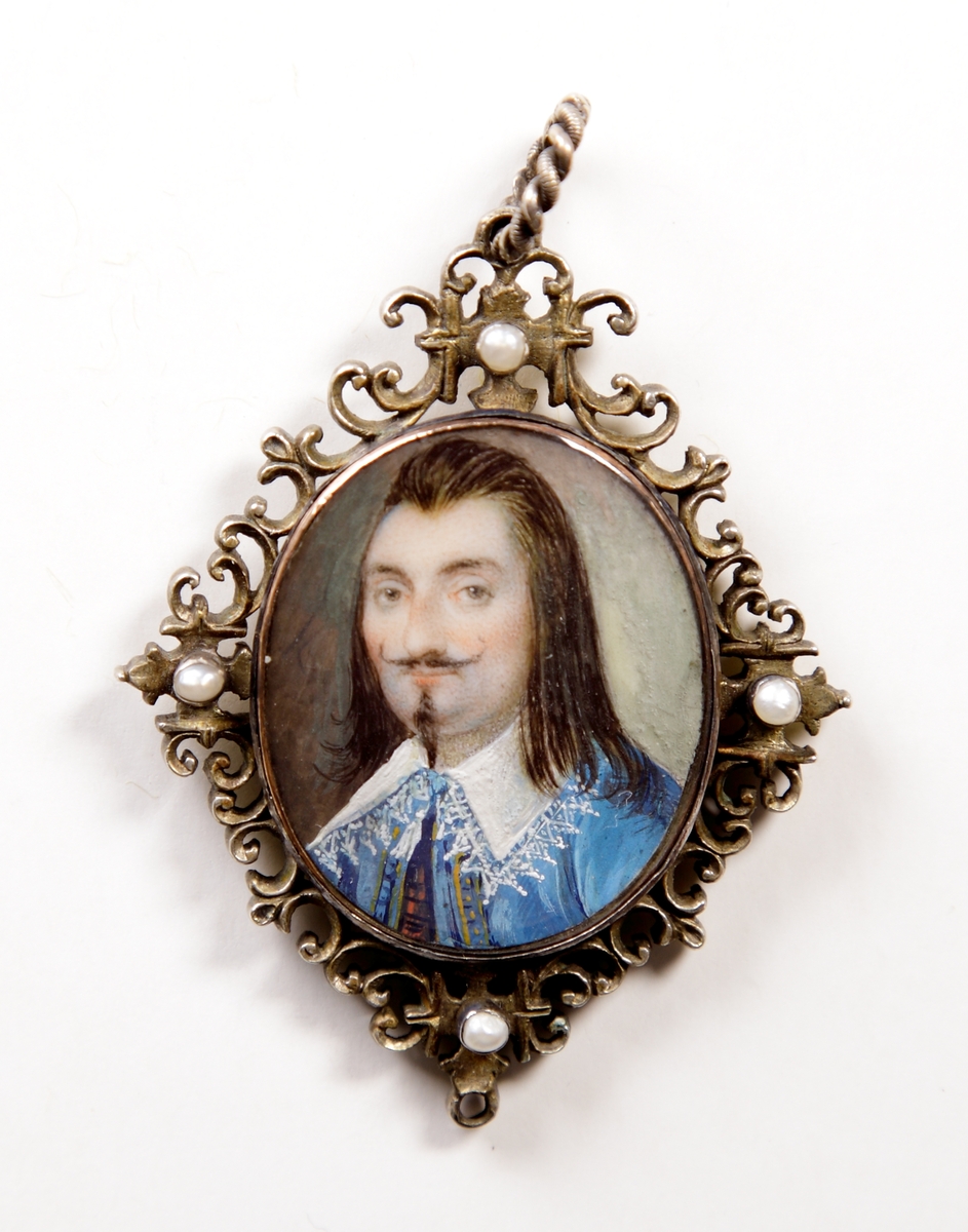 Miniatyrporträtt (medaljong) av man med långt mörkt hår, pipskägg, stor spetskrage och ljusblå jacka. Bröstbild, halvprofil. Snirklig, rombformad ram i förgyllt silver, prydd med fyra pärlor.

Trol. en hovman, tillhörande hovet kring Ludvig XIII av Frankrike. (AB).

Inskrivet i huvudbok 1907. 

Ludvig XIII (på franska Louis XIII) även Ludvig II av Navarra, född 27 september 1601, död 14 maj 1643, var kung av Frankrike och Navarra från 1610 till sin död.
Hans rådgivare, hertigen av Luynes, var 1617-1621 den som egentlige styrde landet. Därefter gick ledningen över till kardinal Richelieu, som snart gjorde sig oumbärlig för kungen.
Han var gift sedan 1615 med Anna av Österrike, och far till Ludvig XIV och Filip I av Orléans, kallad "Monsieur" (1640-1701).
Montering/Ram: Förgylld silverram med pärlor.