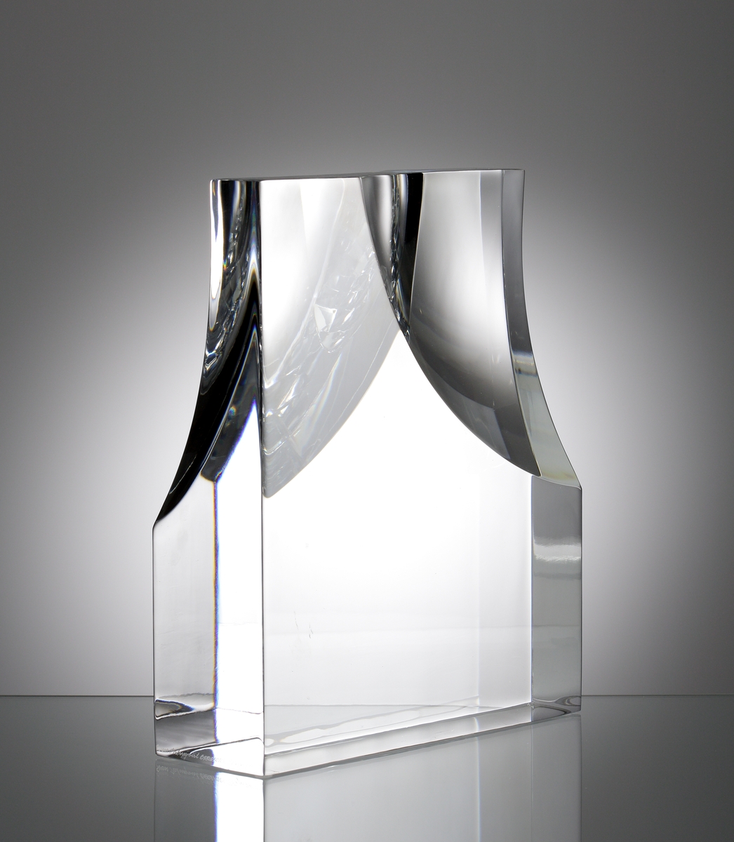 Formgivare: Sven Palmqvist. Glasskulptur, stående rätblocksform. Utförd med slipad konkav yta i främre och bakre vägg.