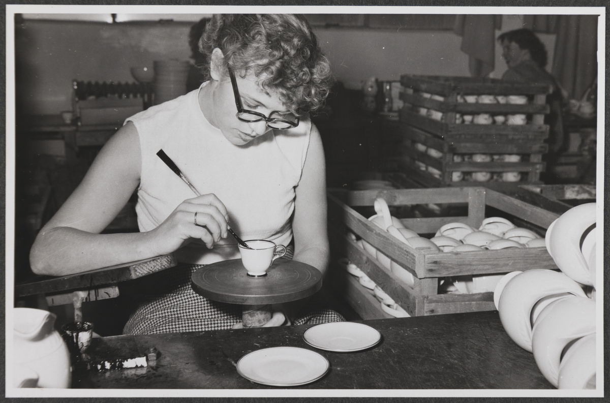 En kvinne maler gullkant på en kopp.