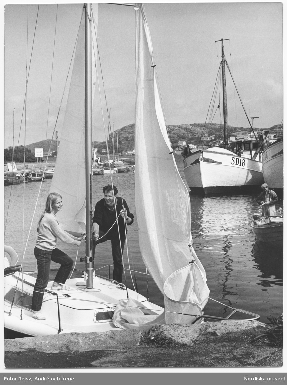 Bohuslän. Båthamn i Fjällbacka. En kvinna och en man i fören på en segelbåt intill kaj.