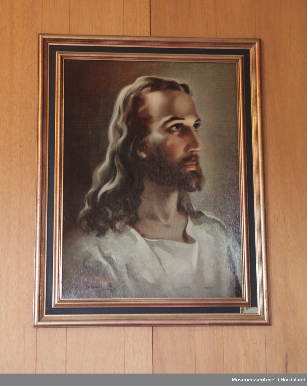 Fargelitografi med forgylt og svart ramme. Bildemotivet viser et portrett av Jesus fra bryst og opp, kledd i hvitt, og i tre fjerdedels profil.