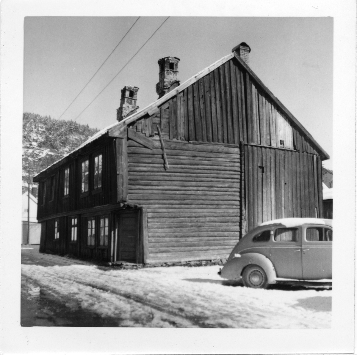 Konggata i Drammen, to-etasjes hus sett fra gata, bil i forgrunnen: Ford V8 1939-modell