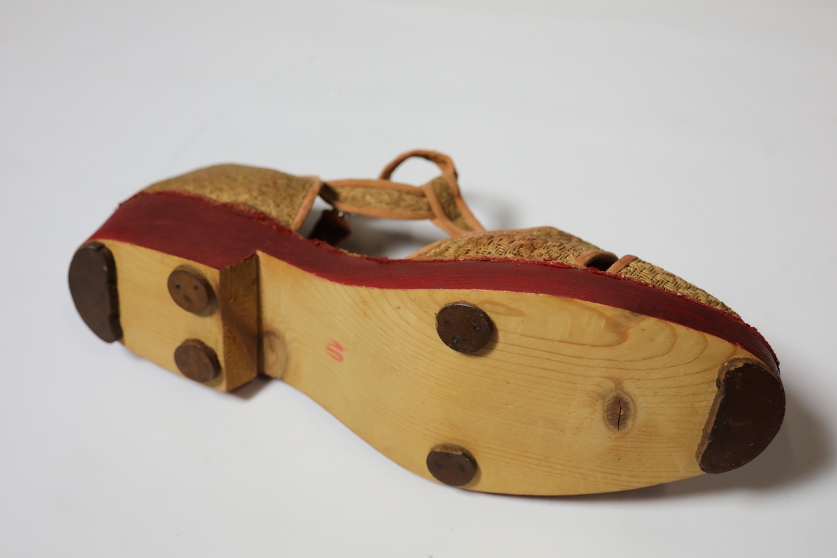 Fotformete tykke såler, åpent midtparti forbundet m/midtstolpe fra tåperti til feste rundt anklene. Bred helkappe.