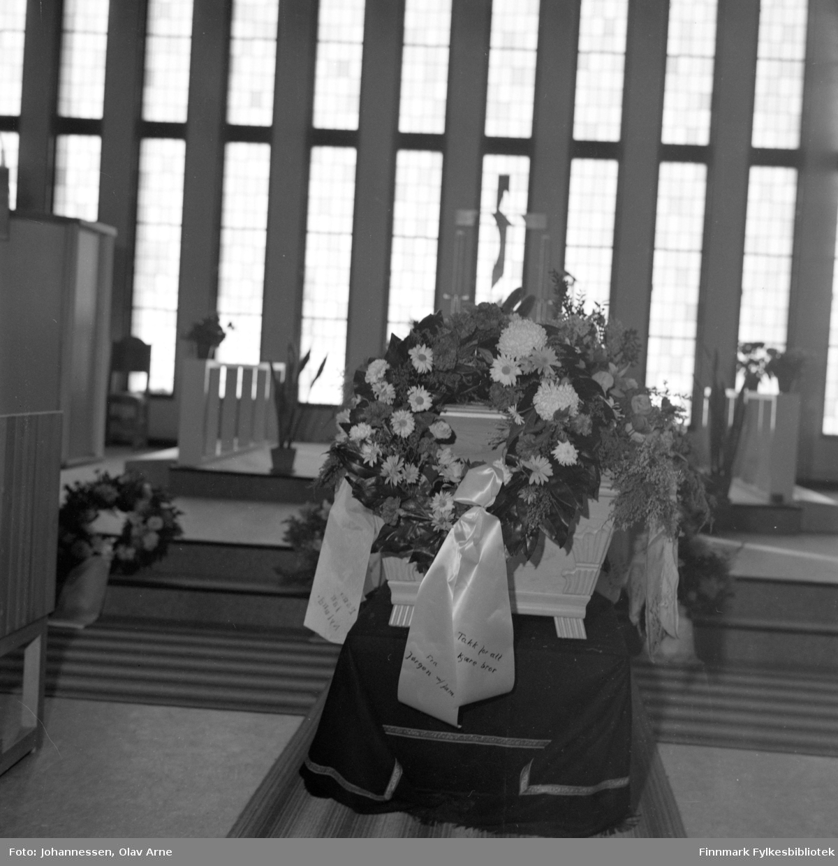 Foto av begravelse i Båtsfjord kirke, med den gamle prekestolen og før glassmaleriet kom på plass