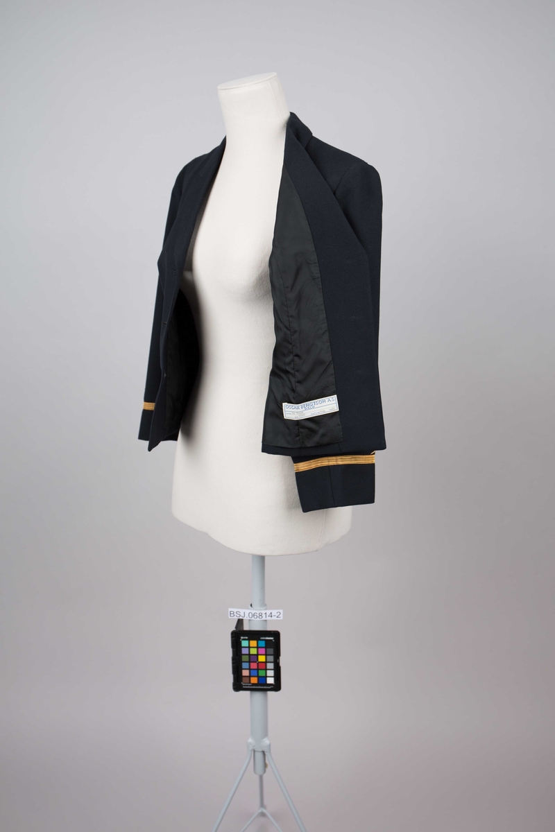 Uniformsjakke med 3 stk. knapper, del av telegrafist-uniform for kvinne. Kort modell med distinksjoner på erme.