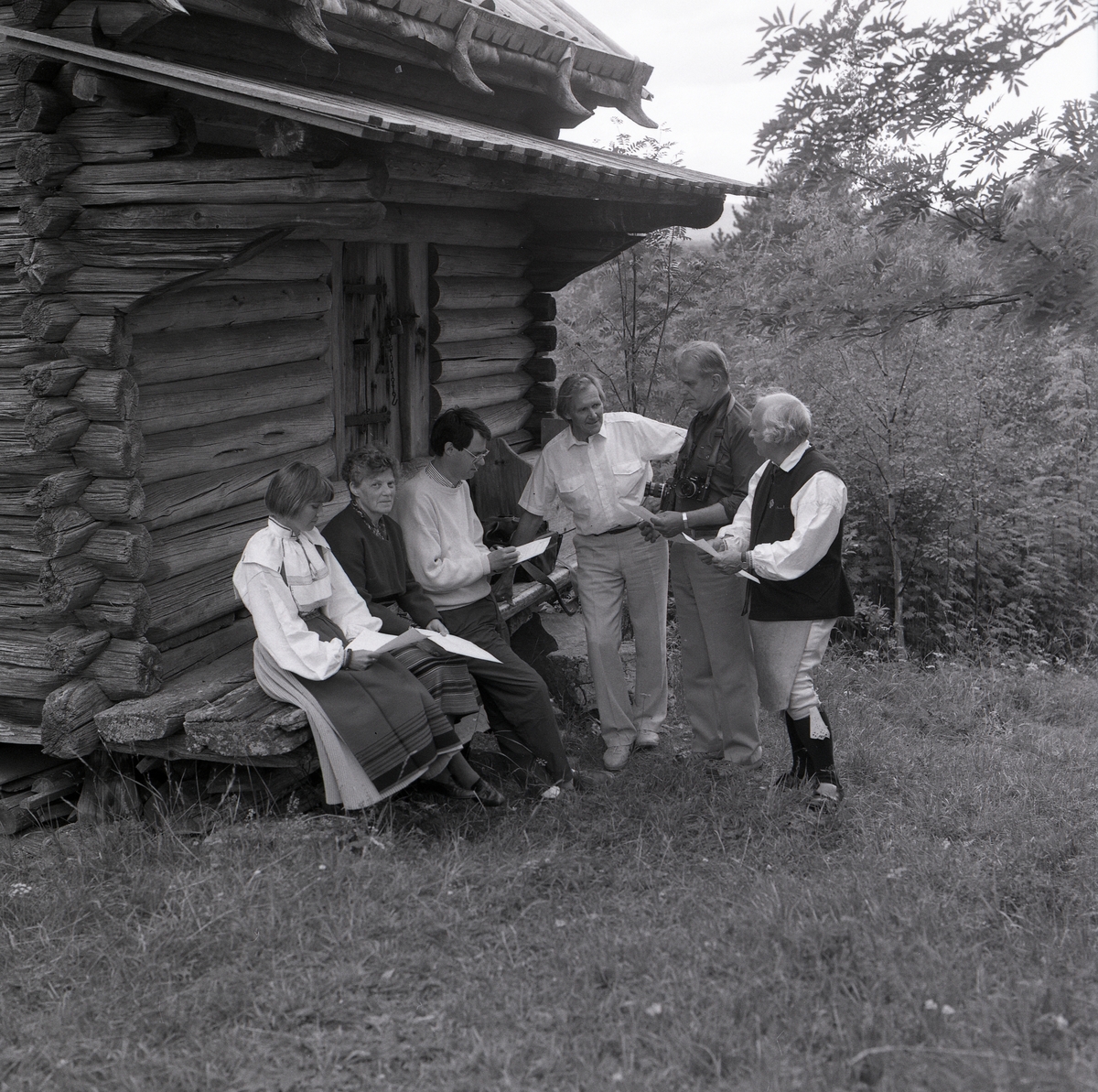 En grupp människor samtalar intill ett härbre under Lärkadagen på Sollerön den 21 juli 1990.
