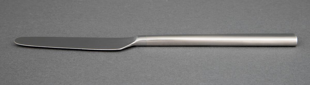 Bordkniv i presset rustfritt stål med rett linje fra bladrygg til skaft, smalt knivblad med små tagger og smalt skaft som tiltar noe i bredde og har rett avslutning.