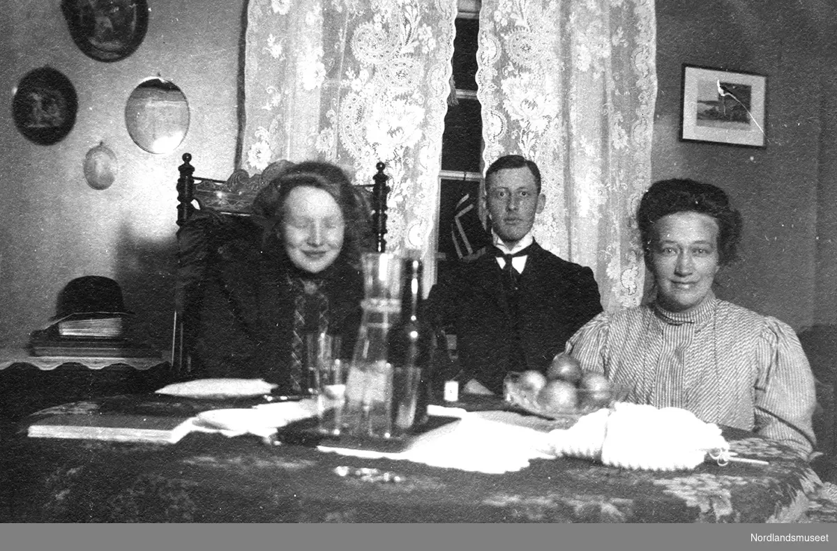 To kvinner og en mann sitter ved et bord ved Sanderud Asyl.