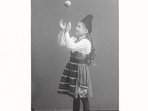 Flickporträtt. Flicka i folkdräkt leker med en boll.