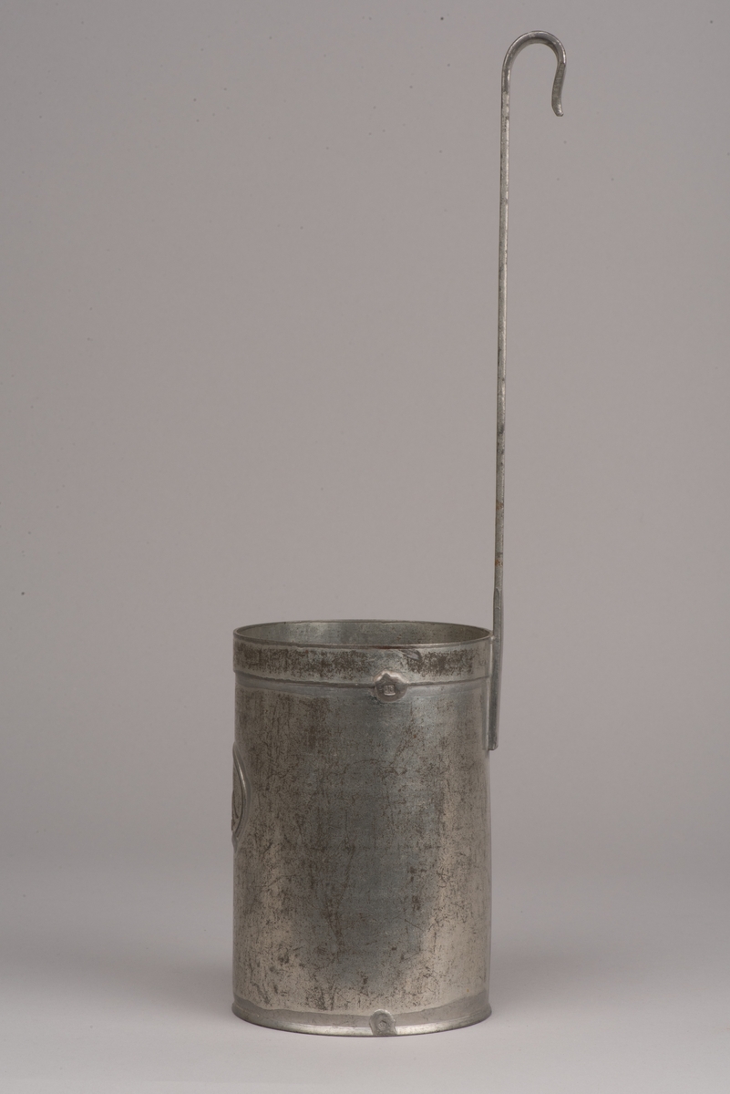 Cylinderformat litermått av plåt.
Handtag i form av ett längre skaft, som avslutas med en böj.
På måttets sida finns en prägling med "1 LITER".