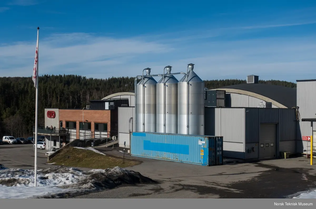 Råvarelager og inngangsparti i kontor- og kantinefløy i sørvendt kortveggfasade på ELKO-fabrikken i Åmot i Modum