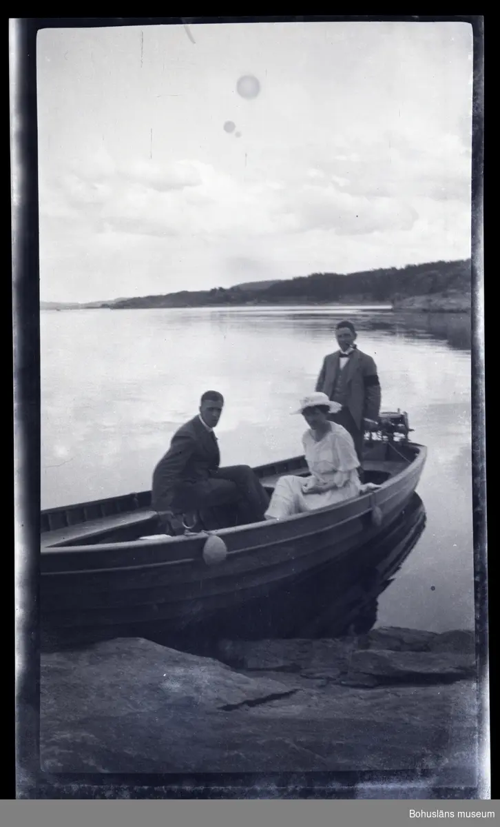 Tre personer i en båt vid en klipphäll.