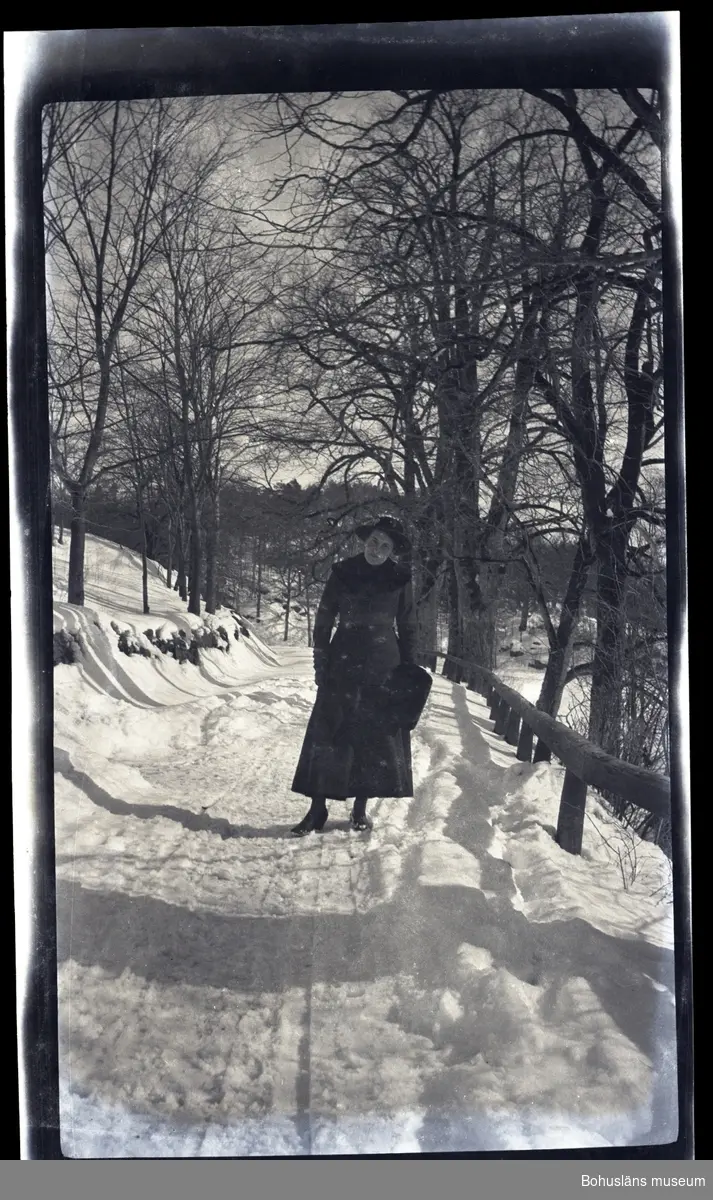 En vinterklädd person ståendes vid en snötäckt allé.