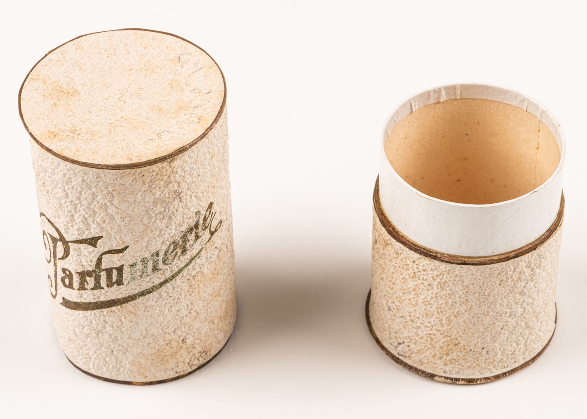 Parfymask i papp, cylinderformad, i glansigt vitt papper med guldfärgad text "Parfumerie".