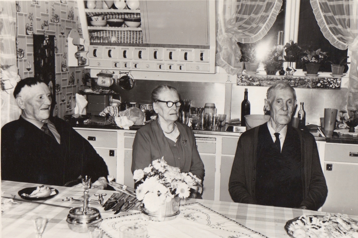 Syskonen Natanael, Alma (gift Ström) och Edvin Bengtsson, samtliga från gården Labacka 1:3, sitter i köket på gården Knabas, Lindbergs socken i Halland. Natanaels enda barn, dottern Nina, hade köpt gården med sin make Gunnar Nilsson. Paret flyttade dit 1962 tillsammans med både Ninas far och farbror.