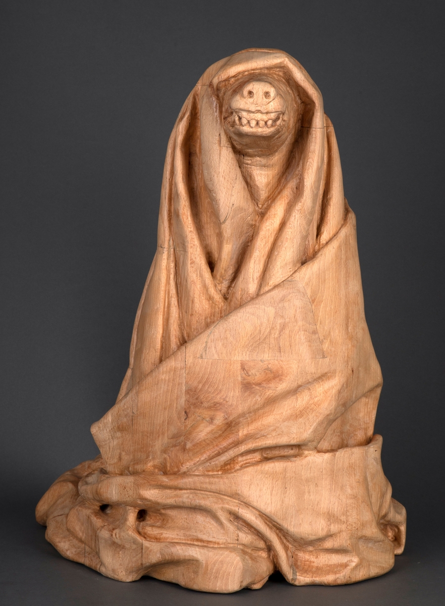 Treskulptur av en ulv foldet inn i et tøystykke.