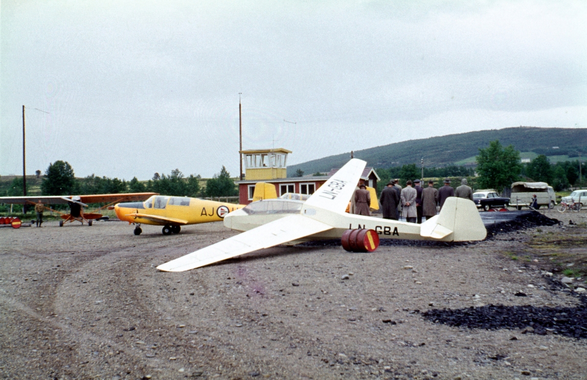 Trondheim Fk.s Bergfalke II/55 og Piper Cub og Luftforsvarets Saab Safir på Røros flyplass. Flyklubbene i Trondheim flyttet kursene sine fra Øysand til Røros flyplass i 1962. Bak i bildet ses flyplassens første ekspedisjonsbygg.