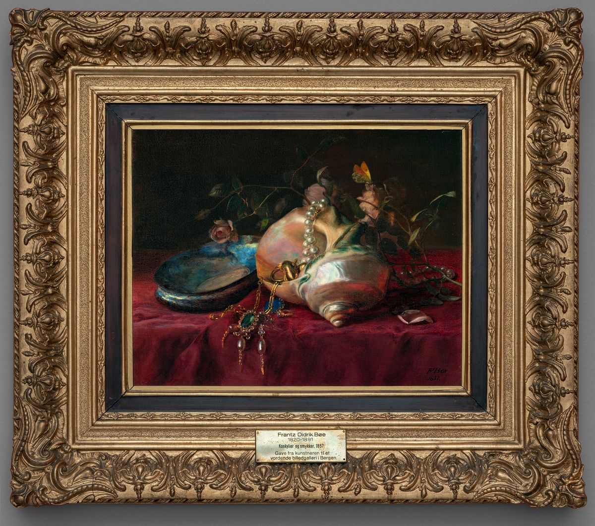 Konkylier, smykker og en kvist røde roser på et bord med fløyelsduk