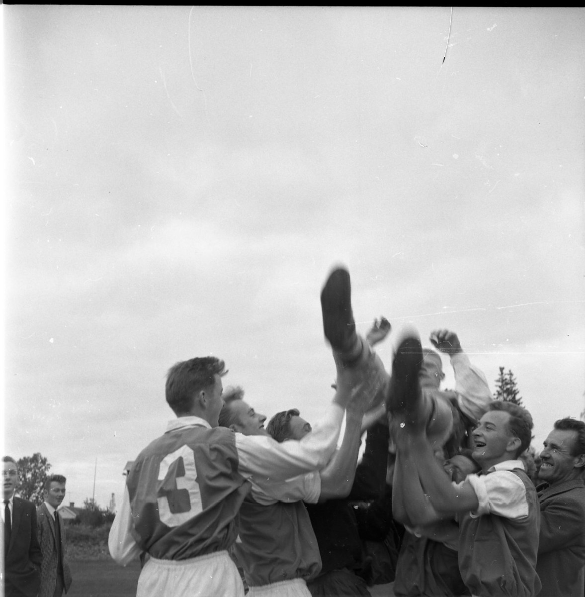 Ett gäng fotbollsspelare hissar deras lagkamrat Karl-Göran Elf i luften. De har matchtröjor på sig.