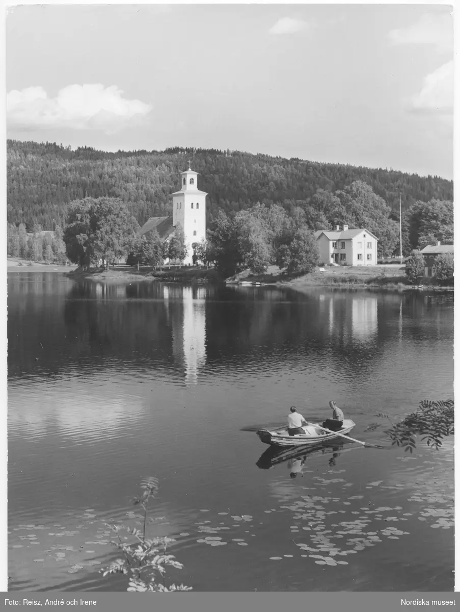 Värmland. Gräsmark kyrka  ibland kallad Uddhedens kapell från 1730-talet vid sjön Udden ”Lillsjön”. Två män i en eka i förgrunden.