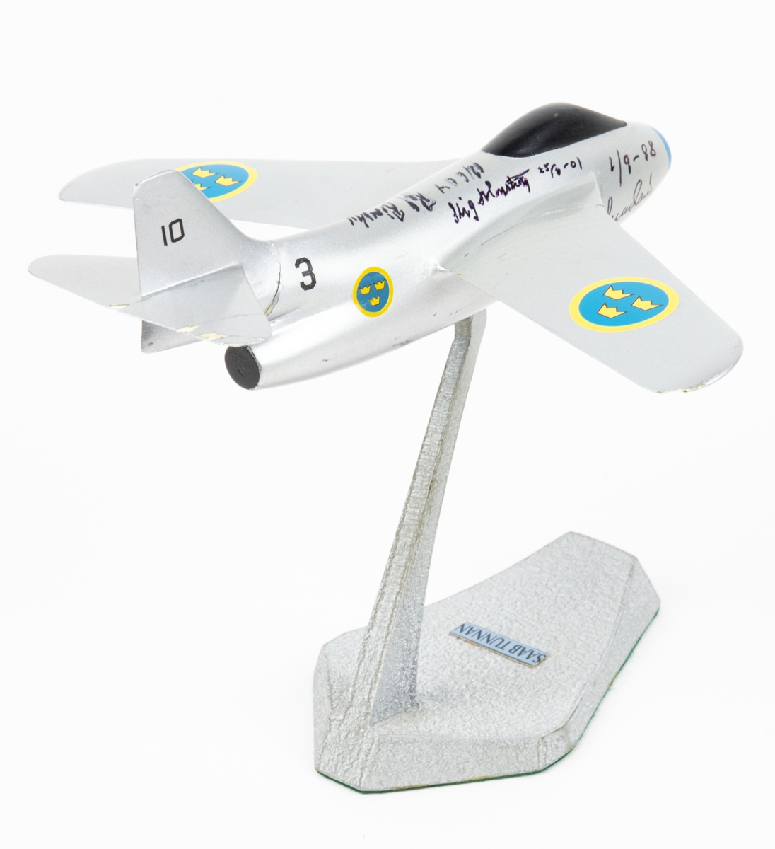 Flygplansmodell Tunnan med fot. På flygplanskroppen finns namnteckningar och årtal.