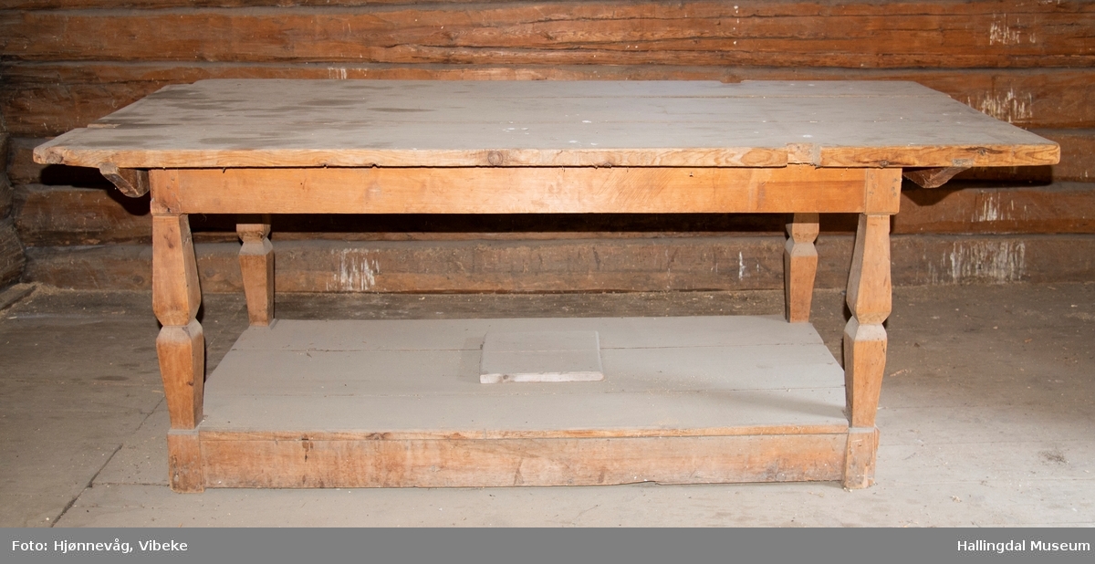 Langbord lagd av tre planker. Bordet ligger oppå et understell med 4 bein som er festet inni en karm med planker oppe og nederst. Nederst er det lagt 3 profilerte planker og det dannes et rom mot gulvet som er 16 cm høyt. Midt i plata (de tre plankene) er det en luke som kan løftes av. Det er skjært ut 4 firkantete hull i bordplata som en løs karming kan settes ned i. Karmen består av 4 "grove" føtter med 2 planker på langsidene og 3 planker på kortsidene. Den er rødmalt.