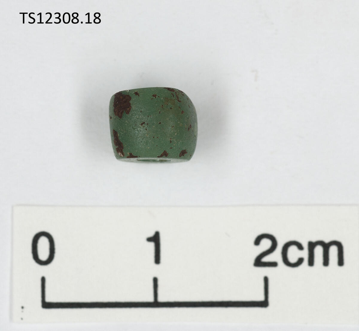 1 stk perle av glass. Opak, Grønn.  Ringformet, med skarpt avskårne endeflater. 0,9 cm i diameter, 0,6 cm tykk.