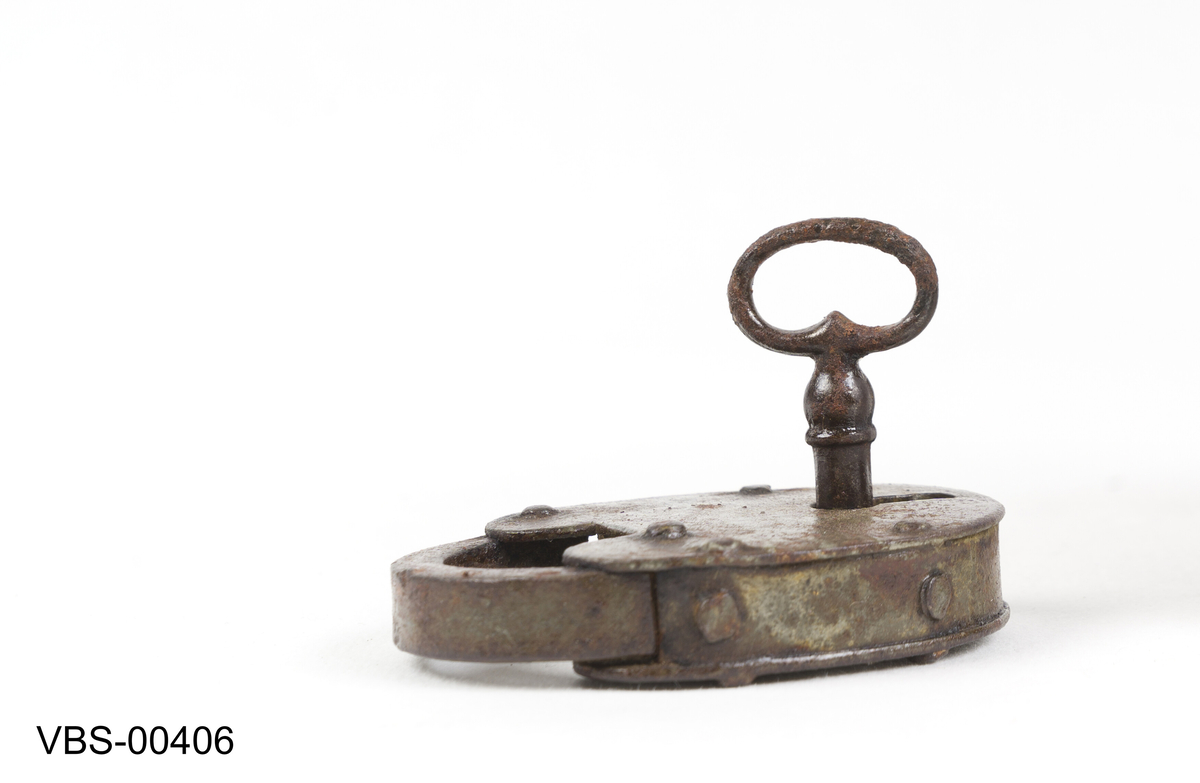 Oval, hjerteformet hengelås med nøkkel. 
Nøkkelen har rund bøyle, firkantet skjegg og hull pipe.